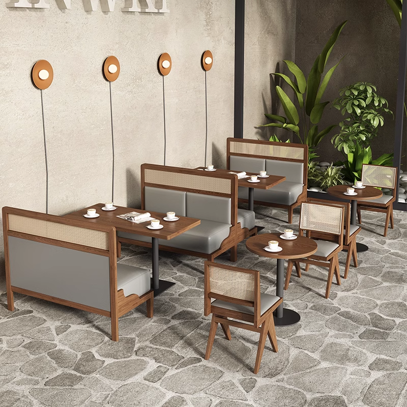 Stylish cafe dining set featuring wooden booth seating with gray cushions, round tables, and wicker-backed chairs in an open indoor-outdoor setting.