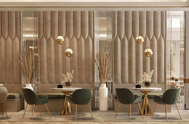 Modern restaurant interior featuring green upholstered chairs with golden bases, elegant marble tables, and minimalist light fixtures, with a sophisticated neutral-colored wall design.