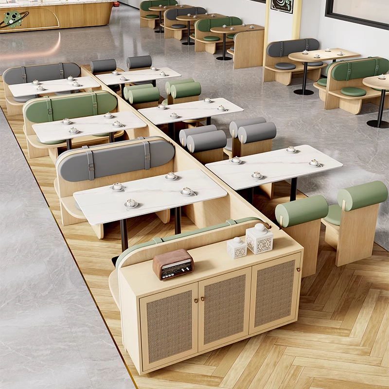  Modern café booth seating arrangement with green, grey, and wooden elements, featuring marble tabletops and sleek designs.