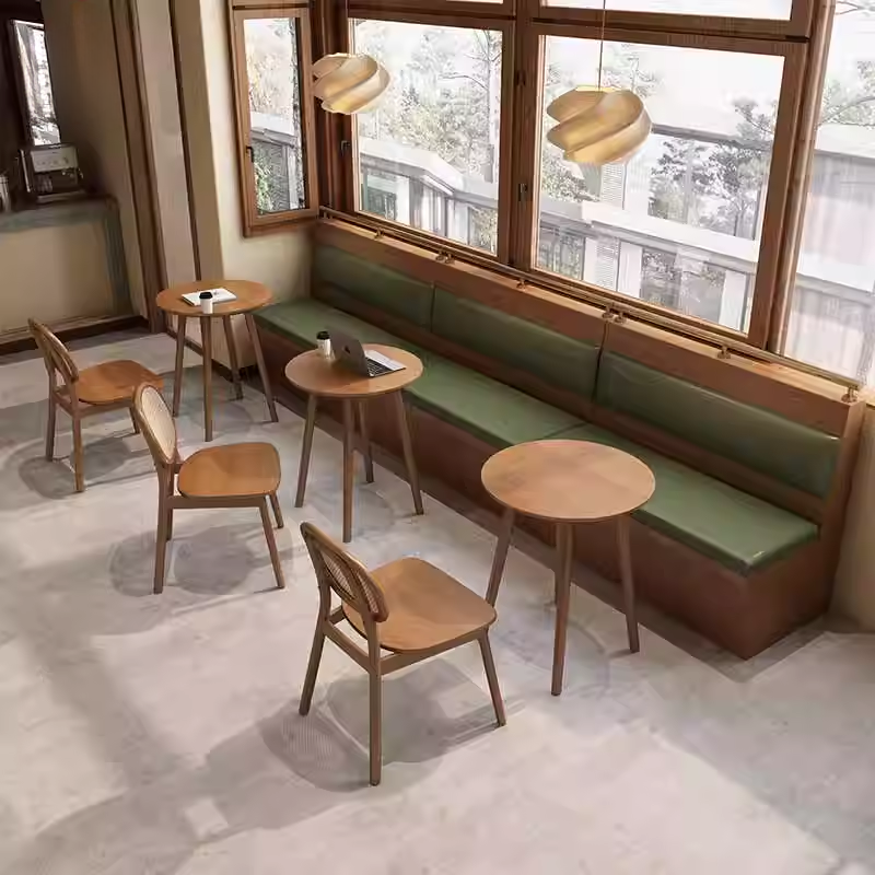 A modern cafe interior with wooden dining chairs, green cushioned booths, and large windows.
