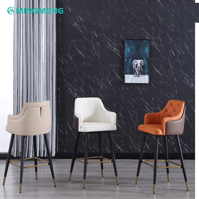 Two brown and white barstools with tufted leather seating and backrests, supported by black metal legs with golden tips.