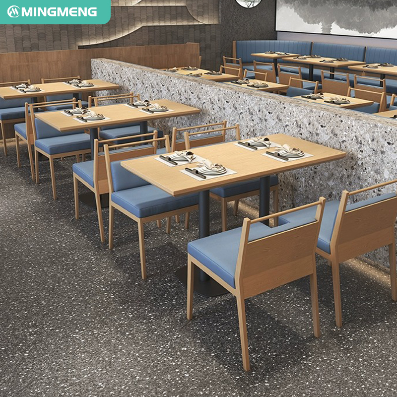 A modern restaurant featuring blue booths, wooden tables, and pendant lights. A nature mural enhances the decor.
